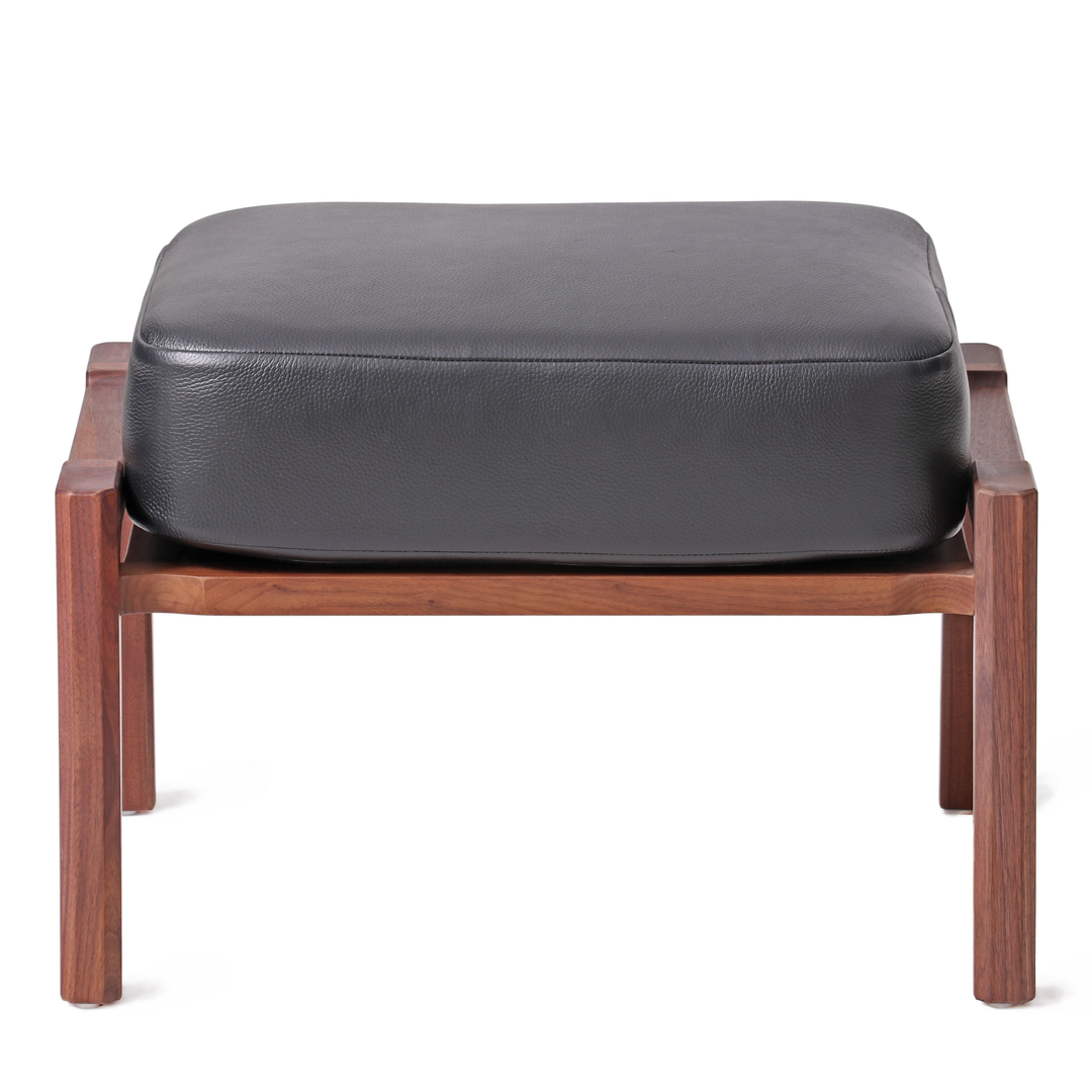 Modern ottoman with natural walnut wooden frame and black leather cushion, ideal for complementing lounge chairs in contemporary home or office decor.