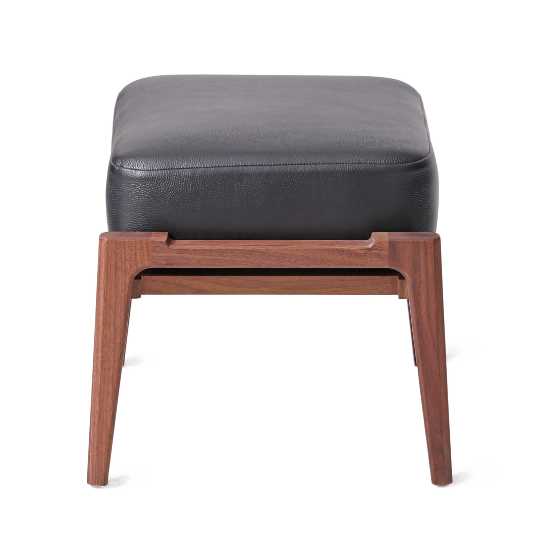 Modern ottoman with natural walnut wooden frame and black leather cushion, ideal for complementing lounge chairs in contemporary home or office decor.